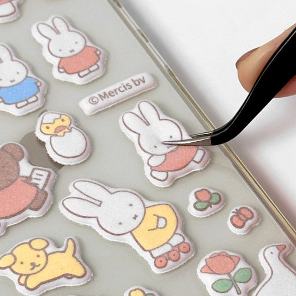 Two officially licensed Miffy Fuzzy Cushion Sticker sheets in cream and mint colors, showcased alongside a decorated phone case and earbud case. The sticker sheets are filled with small, textured, raised stickers depicting Miffy the bunny and her friends engaging in daily activities like baking and gardening.
