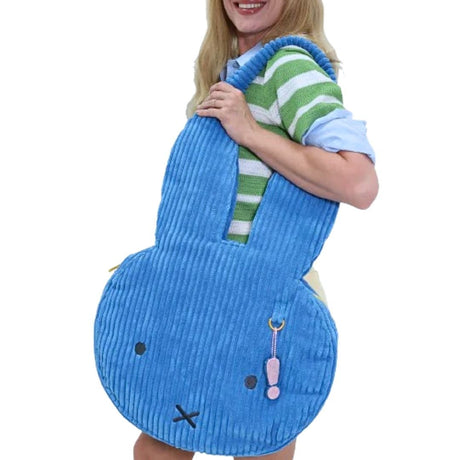 Oversized blue corduroy Miffy shoulder bag, featuring the character's face with an 'X' mouth and dot eyes. Includes a decorative pink exclamations mark charm and is suitable for fans of Miffy.