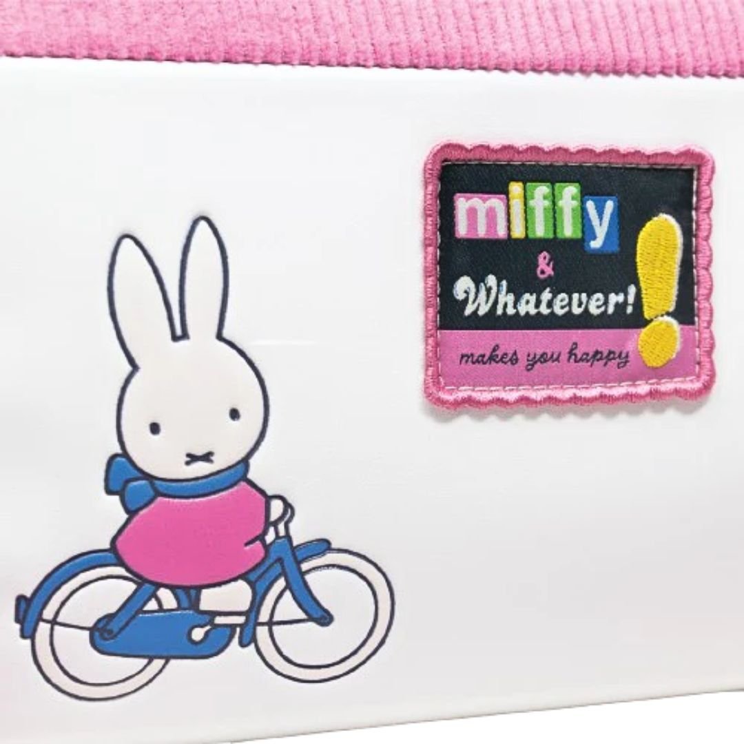 Officially licensed Miffy House-shaped cross-body bag . The bottom PU leather section features a printed or debossed graphic of Miffy riding a bicycle. The top section is pink corduroy, resembling a roof.