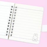 A series of officially licensed Miffy spiral notebooks in pastel pink, blue, and purple, featuring a large magnetic character buckle. The interior shows lined paper with a small Miffy graphic in the bottom corner, highlighting the notebook's functional and cute design.