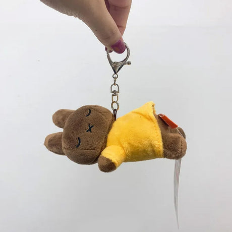 Officially licensed Melanie sleeping plush keychain featuring embroidered closed eyes and an 'X' mouth. Brown plush wearing yellow top. Ideal collectible bag charms, backpack zipper pulls or gift.
