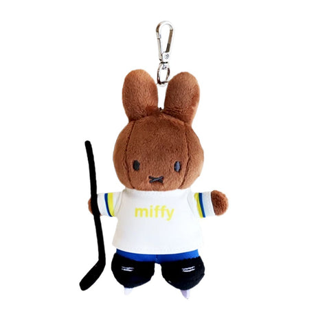 A chocolate-brown, officially licensed Miffy's Melanie plush keychain dressed in a white hockey jersey and blue shorts. The bunny is holding a black hockey stick and wearing black ice skates, attached to a silver metal clip.