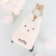 An officially licensed Miffy plush mini backpack pouch keychain in brown, ivory, pink, and black, featuring a gold bunny shaped clip.