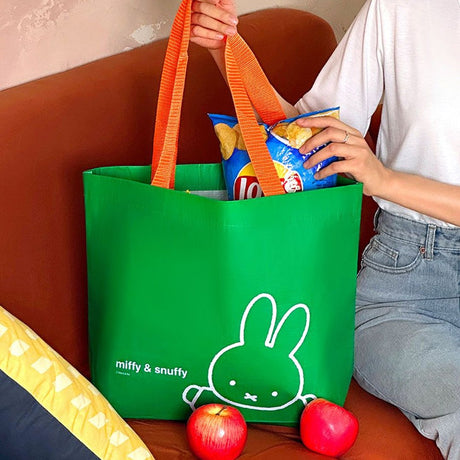 Officially licensed Miffy & Snuffy Reusable Tote Bags . The bags are Made from durable, wipeable tarpaulin material, featuring one in bright green with orange handles and Miffy. Tote bag filled the snack. Ideal for shopping, groceries, or carrying goods.