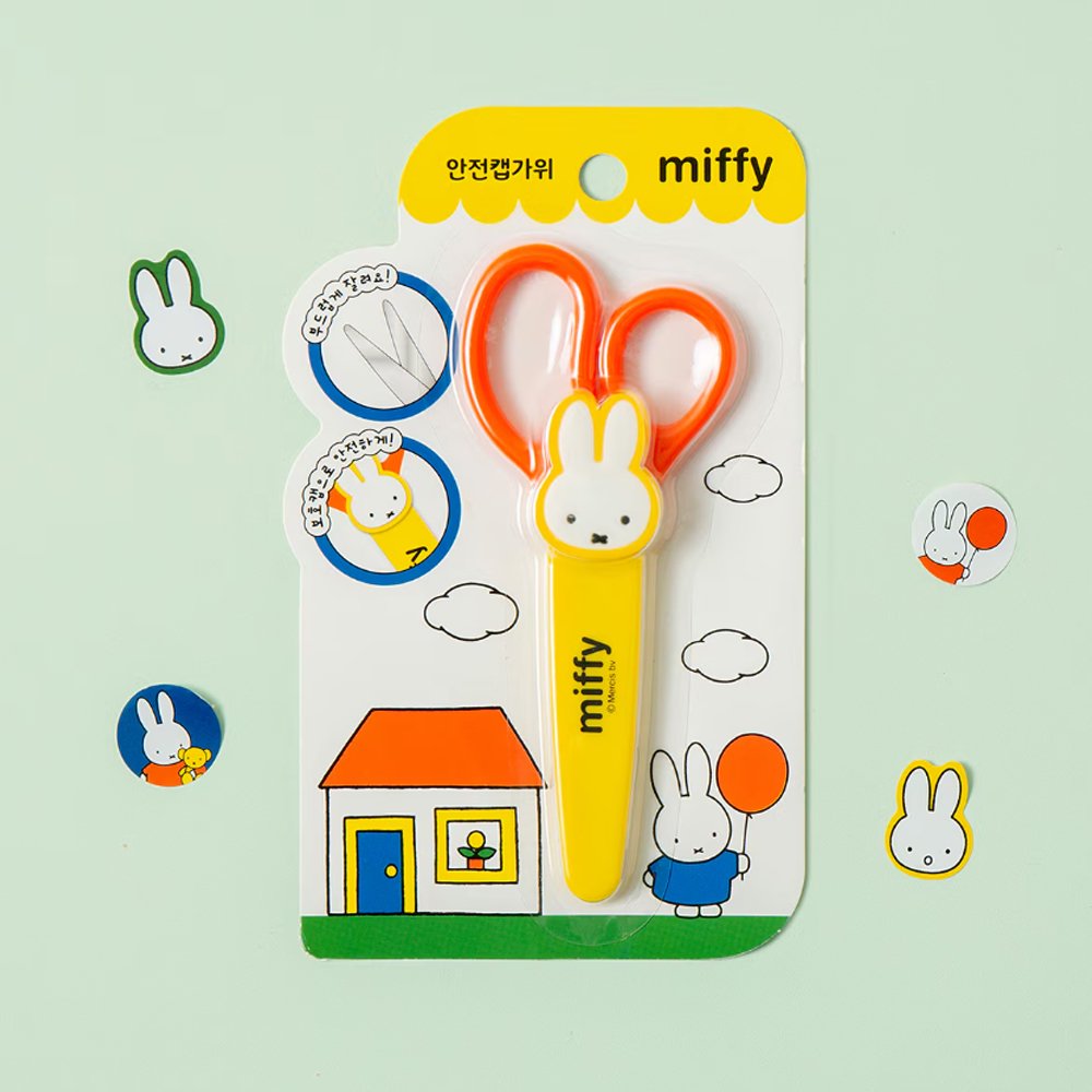 An officially licensed pair of Miffy safety scissors packaged on a colorful backing card, featuring bright orange handles and a protective yellow cap adorned with a die-cut Miffy bunny head.

