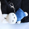Officially licensed Miffy sleeping plush keychain featuring embroidered closed eyes and an 'X' mouth. Miffy plush wearing green top. The soft plush toy keychain attached to a black  backpack .