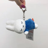 Officially licensed Miffy sleeping plush keychain featuring embroidered closed eyes and an 'X' mouth. Miffy plush wearing blue top. Ideal collectible bag charms, backpack zipper pulls or gift.