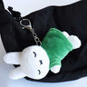 Officially licensed Miffy sleeping plush keychain featuring embroidered closed eyes and an 'X' mouth. Miffy plush wearing green top. The soft plush toy keychain attached to a black  backpack .