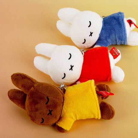 Set of three officially licensed Miffy plush sleeping keychains. The soft dolls include two white Miffy plush (wearing blue and red top ) and one brown Miffy plush(wearing a yellow top), all with embroidered closed eyes and an 'X' mouth. Ideal collectible bag charms or backpack zipper pulls.