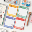 A collection of four officially licensed Miffy sticky note pads in soft shades of red, yellow, green, and blue. Each pad features a white grid writing area decorated with minimalist illustrations of Miffy, a dog, flowers, and beach balls.