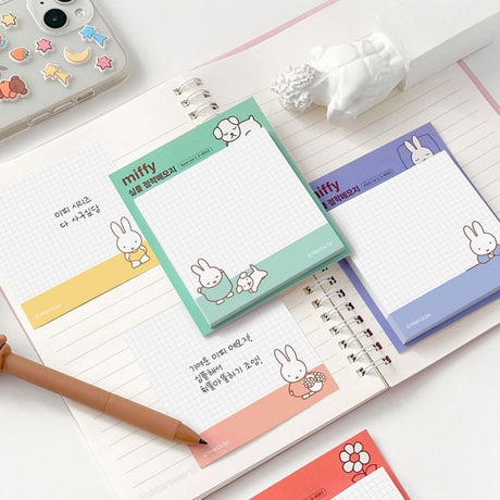 A collection of four officially licensed Miffy sticky note pads in soft shades of red, yellow, green, and blue. Each pad features a white grid writing area decorated with minimalist illustrations of Miffy, a dog, flowers, and beach balls.
