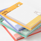 A collection of four officially licensed Miffy sticky note pads in soft shades of red, yellow, green, and blue. Each pad features a white grid writing area decorated with minimalist illustrations of Miffy, a dog, flowers, and beach balls.