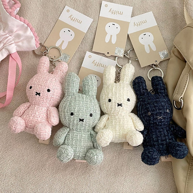 Four officially licensed Miffy textured tweed plush keychains lined up in pink, sage green, cream, and navy blue with attached silver keyrings