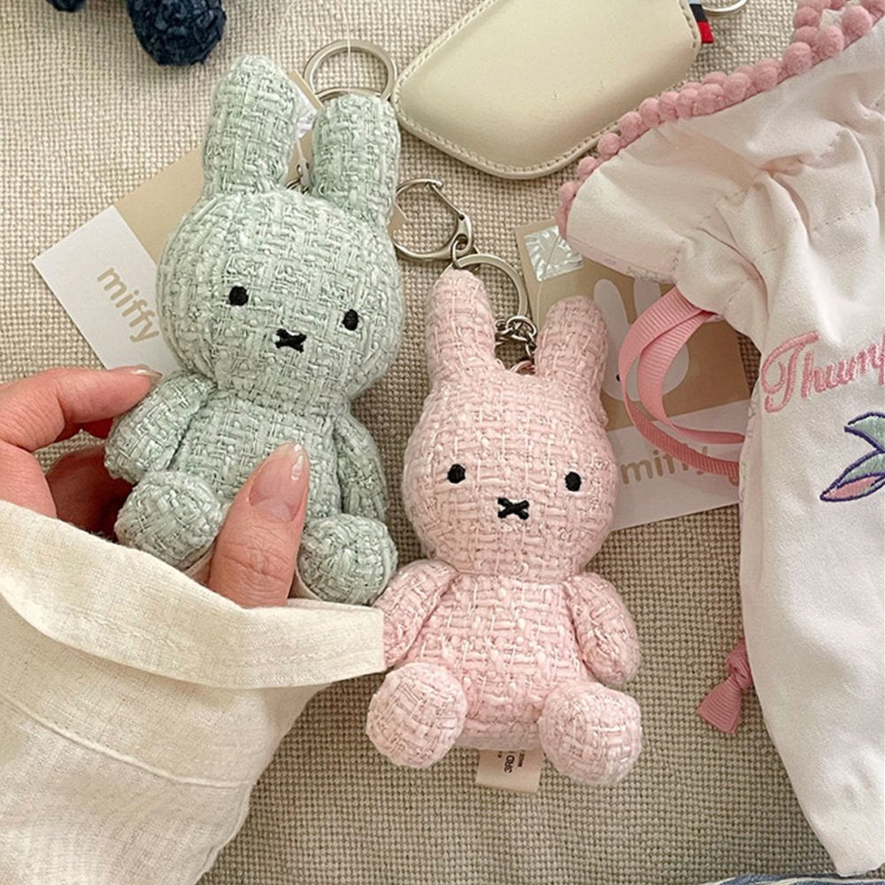 Four officially licensed Miffy textured tweed plush keychains lined up in pink, sage green, cream, and navy blue with attached silver keyrings