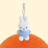 Four officially licensed Miffy plush keychains wearing knit sweaters in orange, green, light blue, and dark blue standing together. Each plush includes an attached silver chain with a lobster clasp at the top.