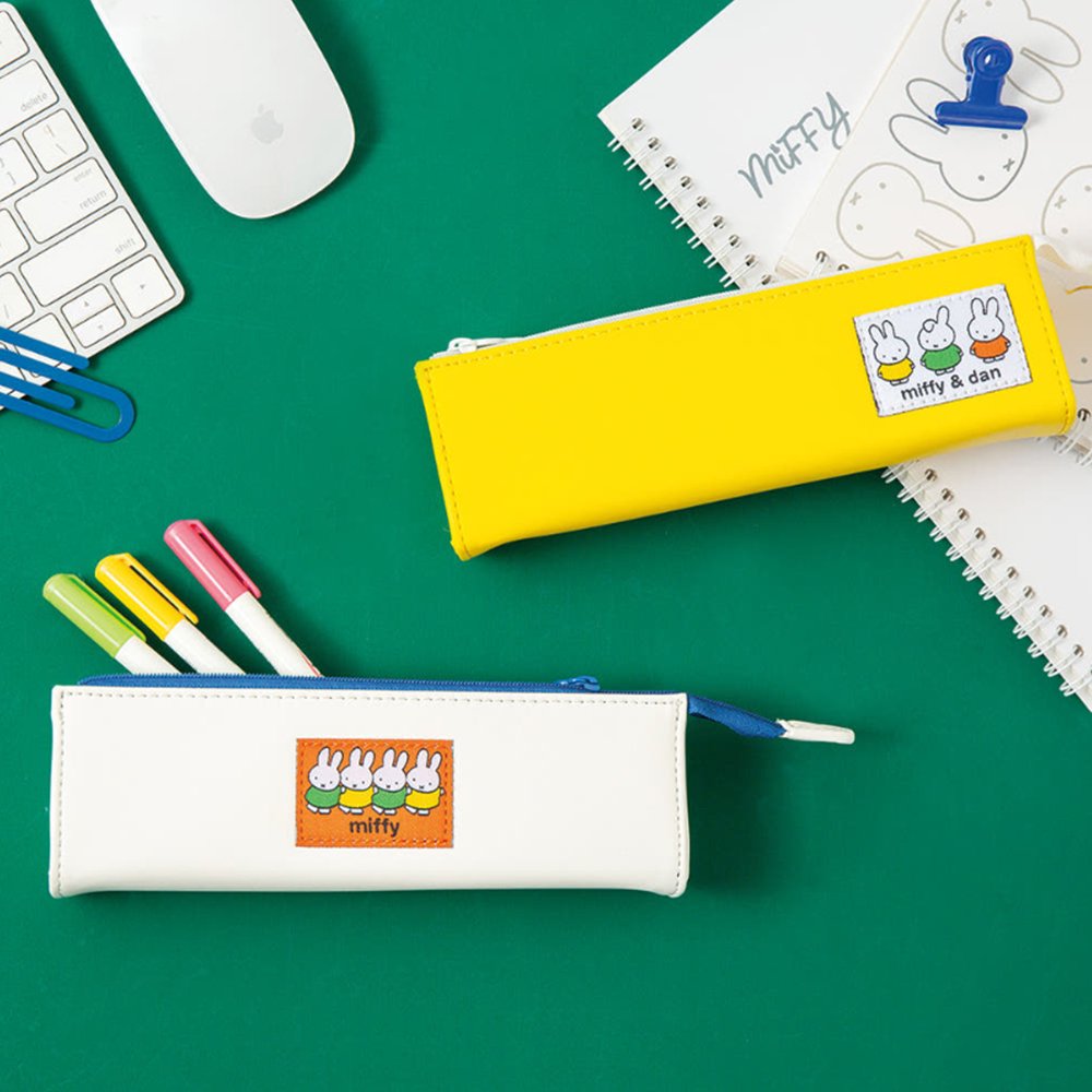 Two officially licensed slim, triangular Miffy pencil cases, featuring one in bright yellow with a white zipper and a "miffy & dan" patch, and the other in cream-colored with a bold blue zipper and a red "miffy" patch.
