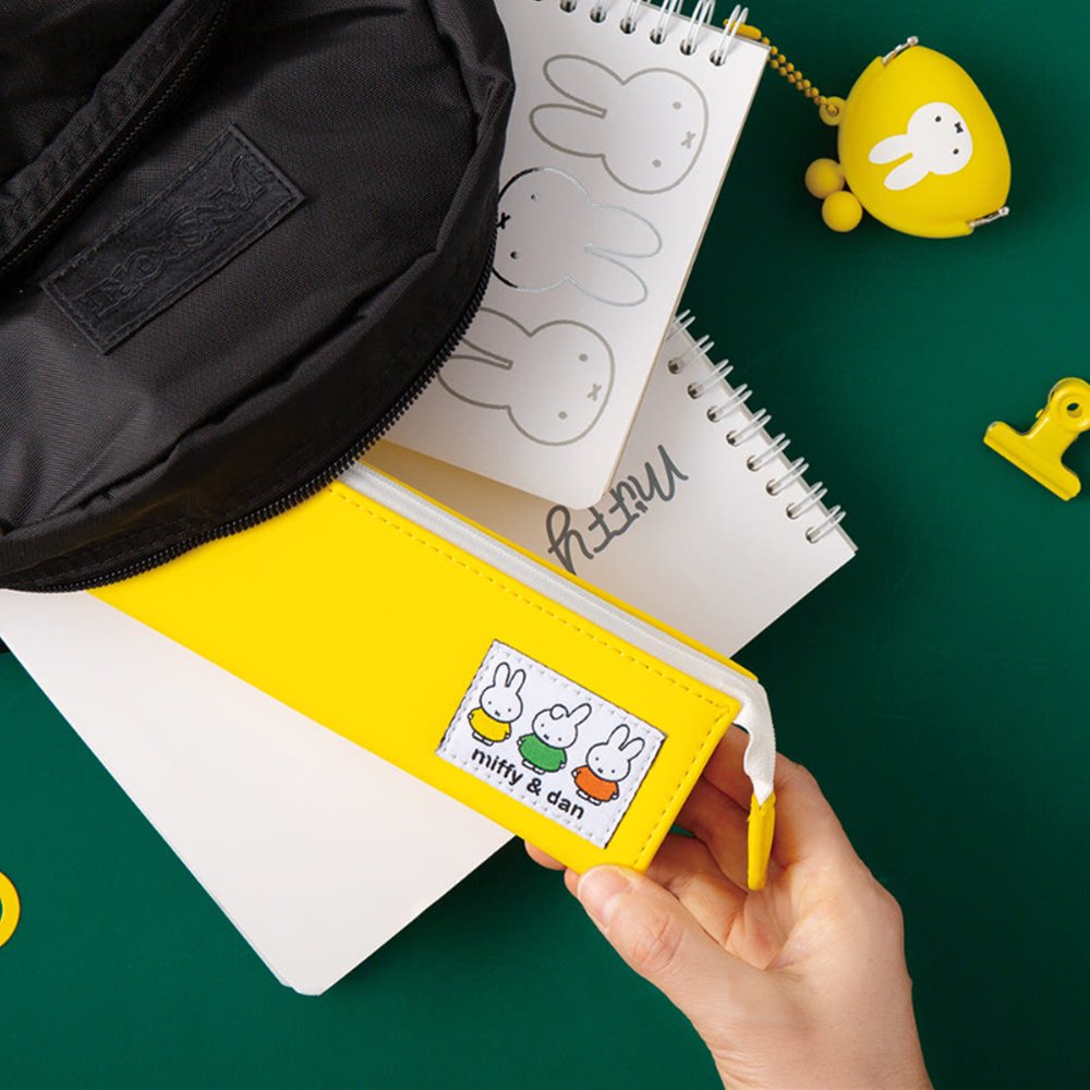 Two officially licensed slim, triangular Miffy pencil cases, featuring one in bright yellow with a white zipper and a "miffy & dan" patch, and the other in cream-colored with a bold blue zipper and a red "miffy" patch.
