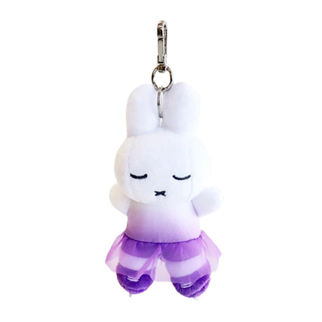 A white, officially licensed Miffy plush keychain dressed as a figure skater in a purple ombré dress with a tulle skirt. The bunny has closed eyes and tiny purple skates, attached to a silver metal clip.

