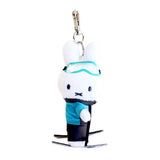 An officially licensed Miffy plush keychain featuring a white Miffy bunny character dressed in a winter skiing outfit with a teal jacket, black pants, mint-green goggles, and holding ski poles on miniature skis.