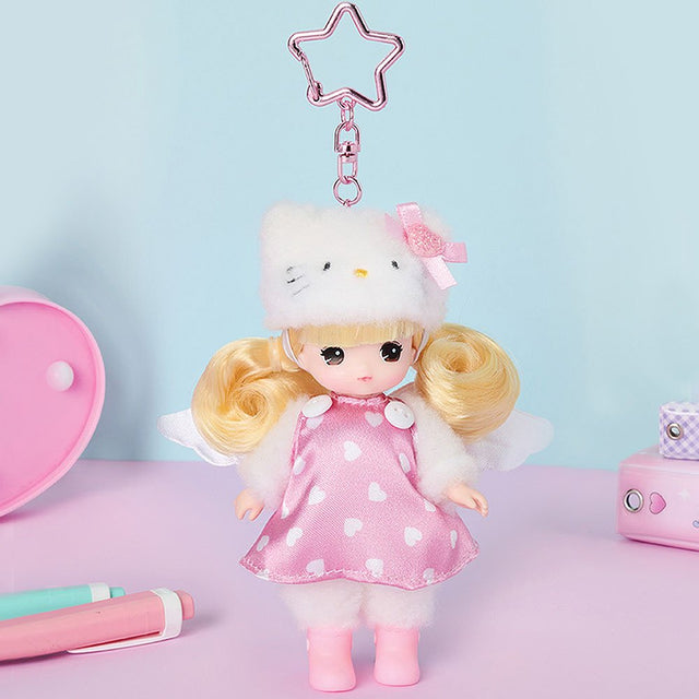 Little mimi doll with blonde hair and a pink dress, holding a Hello Kitty cat plushie, on a light blue background.