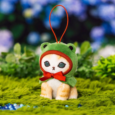 An officially licensed Mofusand plush mascot keychain featuring a small ginger tabby cat wearing a green frog-themed hood with a red bow