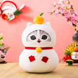 An officially licensed plush toy of a grey tabby cat dressed as a Japanese Kagami Mochi rice cake, featuring a small mandarin on its head