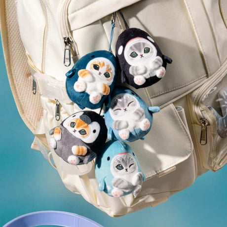 Five officially licensed Mofusand plush keychains featuring small cats wearing various marine animal costumes like blue sharks, a black orca, and a grey penguin. The cats are depicted with cute expressions, including one winking and one with its eyes closed in a happy smile.
