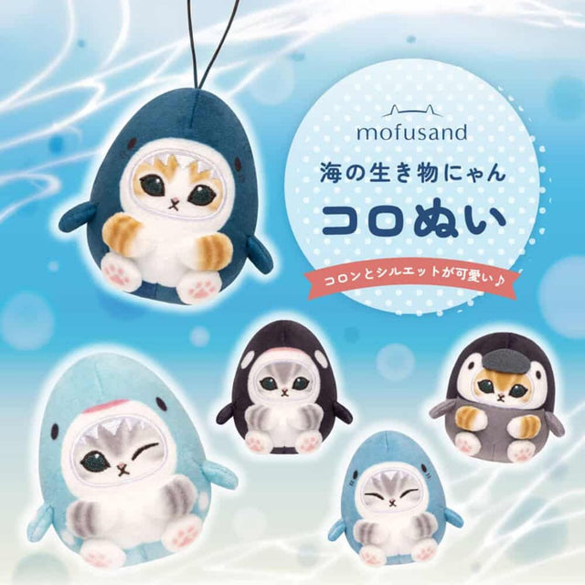 Five officially licensed Mofusand plush keychains featuring small cats wearing various marine animal costumes like blue sharks, a black orca, and a grey penguin. The cats are depicted with cute expressions, including one winking and one with its eyes closed in a happy smile.