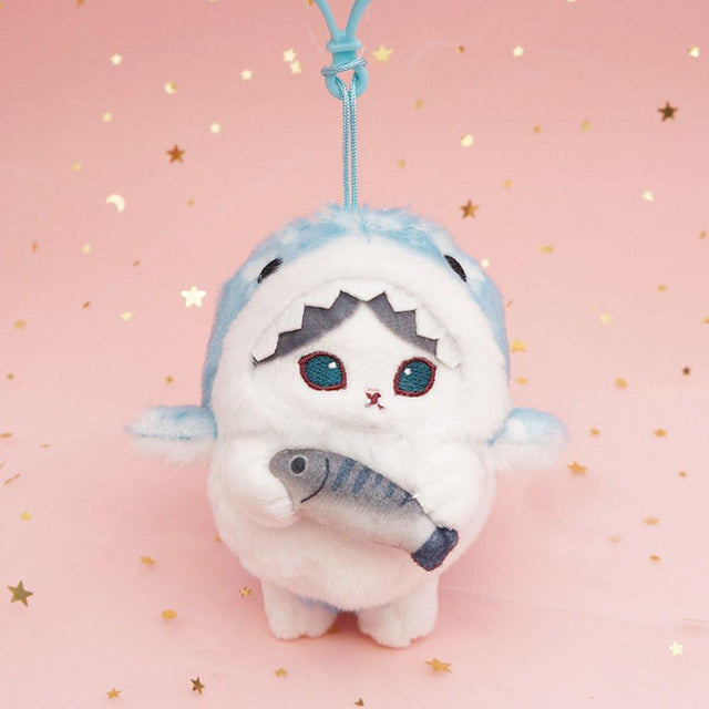 An officially licensed Mofusand shark cat plush keychain featuring a fluffy blue tabby kitten wearing a blue shark onesie with embroidered details