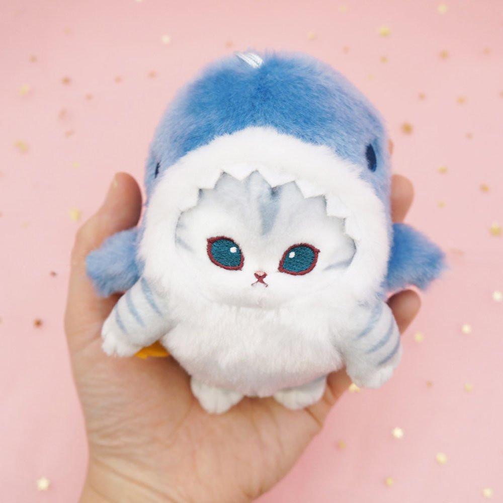 An officially licensed Mofusand shark cat plush keychain featuring a fluffy gray tabby kitten wearing a blue shark onesie with embroidered details