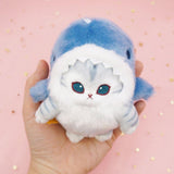 An officially licensed Mofusand shark cat plush keychain featuring a fluffy gray tabby kitten wearing a blue shark onesie with embroidered details