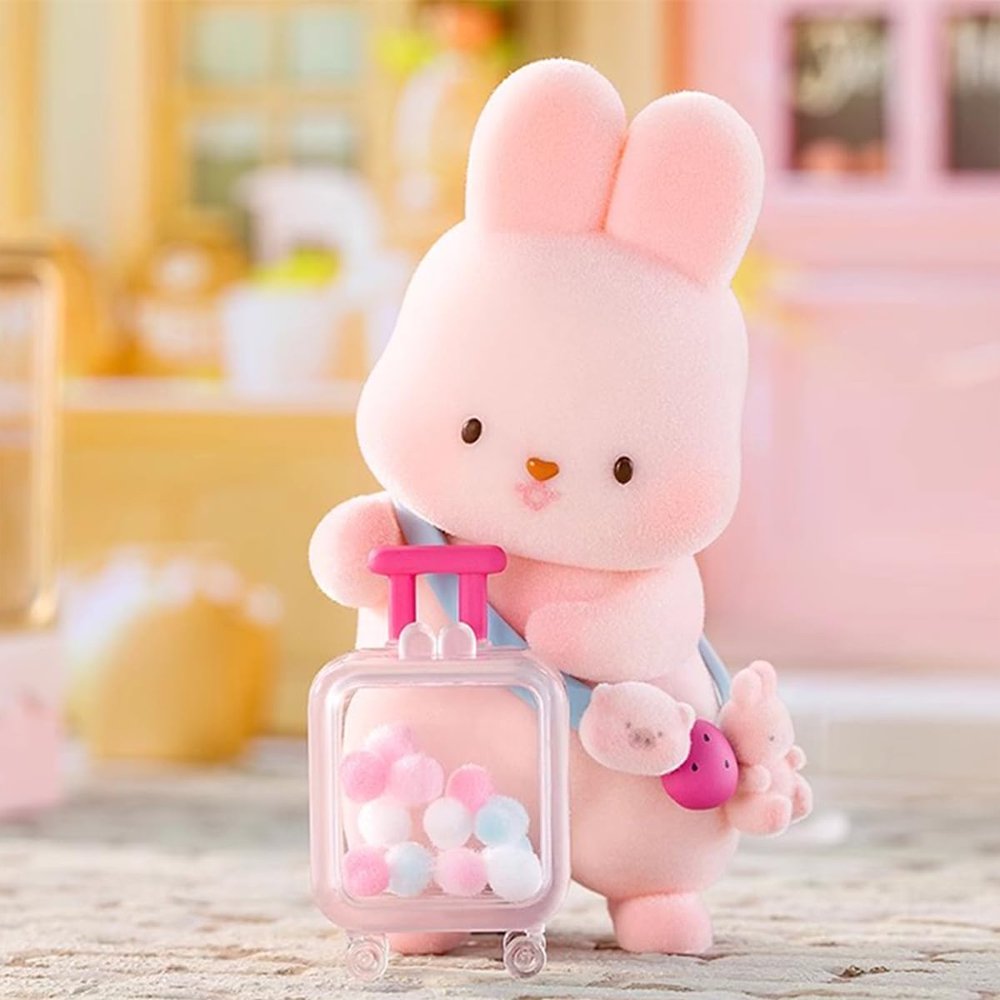 A group of officially licensed Momo Bunny Strawberry Town figures displayed in a miniature outdoor garden setting. The pink bunnies are dressed in various cute outfits, including a snowman suit, a pilot cap, and one sitting inside a strawberry-patterned teacup.
