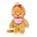 Officially licensed Monchhichi girl plush doll featuring unique golden-beige fur, a long tail, and a cute vinyl face with freckles. The doll has a bright red ribbon tied on its head and wears a white bib with a pink-and-white checkered border that reads "Monchhichi".
