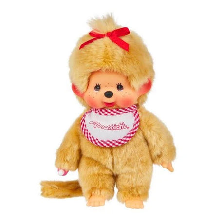 Officially licensed Monchhichi girl plush doll featuring unique golden-beige fur, a long tail, and a cute vinyl face with freckles. The doll has a bright red ribbon tied on its head and wears a white bib with a pink-and-white checkered border that reads "Monchhichi".
