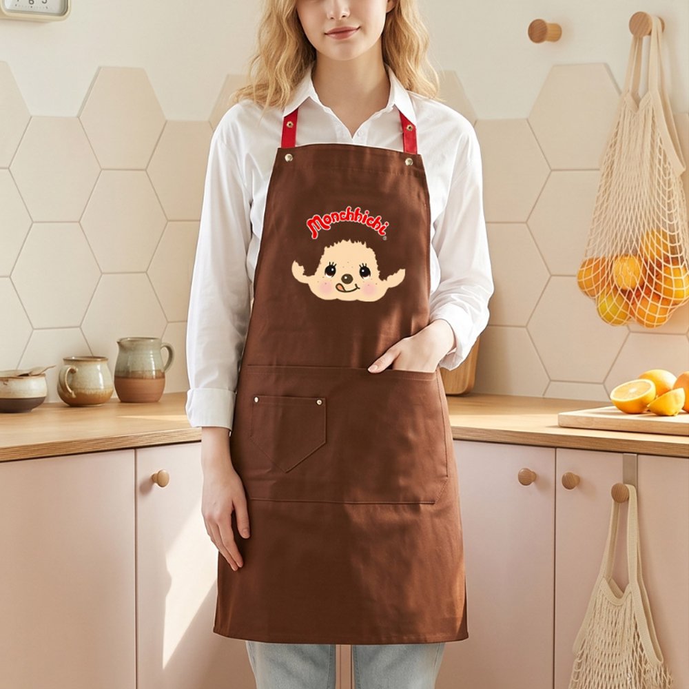 An officially licensed brown Monchhichi apron with red adjustable snap-button neck straps and front utility pockets
