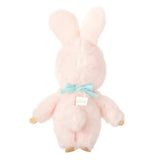 An officially licensed Chimutan bunny plush with fluffy pink fur and long ears, sitting inside a "Monchhichi Friends" decorative box. The plush is wearing a light blue bib with its name printed in red script.