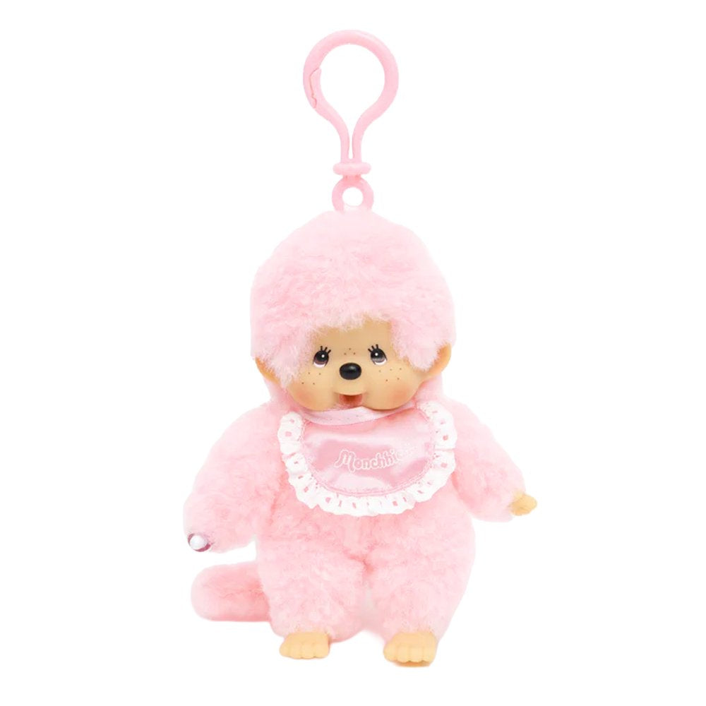 Officially licensed Monchhichi plush keychain doll featuring soft pastel pink fur and a matching pink plastic clip attached to its head. The doll has a freckled vinyl face and wears a shiny pink satin bib with a white lace border reading "Monchhichi".
