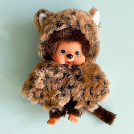 Officially licensed by Sekiguchi Japan, Monchhichi girl dressed in a leopard-print hood complete with cat ears, tail with her signature thumb-sucking pose. she’s perfect for cuddling, displaying, or gifting to Monchhichi fans of all ages.