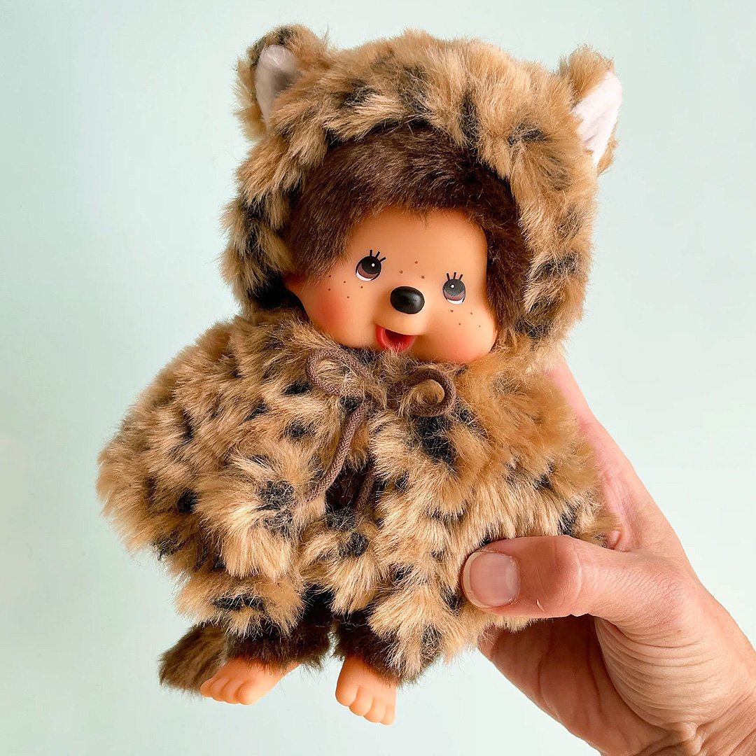 Officially licensed by Sekiguchi Japan, Monchhichi girl dressed in a leopard-print hood complete with cat ears, tail with her signature thumb-sucking pose. she’s perfect for cuddling, displaying, or gifting to Monchhichi fans of all ages.