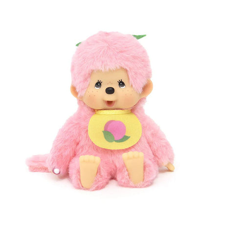 An officially licensed, Peach pink color , Peach -themed Monchhichi plush doll has a tan ABS face, brown eyes, freckles, wear a Peach -print bib, and a green stem detail on its head. Monchhichi plush a soft, fluffy texture. Ideal for collection as a charming gift, or for home decor