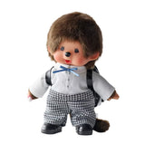 An officially licensed Monchhichi plush doll dressed in a school uniform with houndstooth pants and wearing a black patent leather backpack on its back