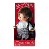 An officially licensed Monchhichi plush doll dressed in a school uniform with houndstooth pants and wearing a black patent leather backpack on its back