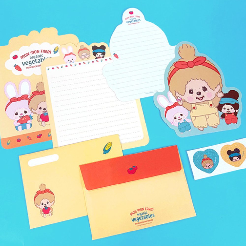 An officially licensed Monchhichi letter writing set displayed with die-cut stationary paper in pink and yellow themes, matching envelopes, and heart sealing stickers