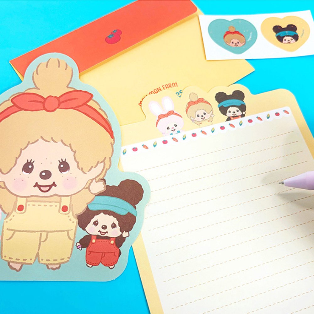 An officially licensed Monchhichi letter writing set displayed with die-cut stationary paper in pink and yellow themes, matching envelopes, and heart sealing stickers