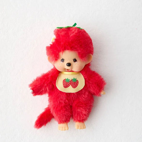 A single strawberry-themed Monchhichi plush doll. It has bright red fur, a tan ABS face with freckles, and wears a yellow bib featuring two strawberries. The doll's red head is topped with a green stem and leaves, and a small white flower.