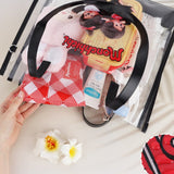 An officially licensed Monchhichi clear tote bag with a removable red polka-dot zippered inner pouch and long shoulder straps, available in black and brown trim