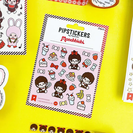 A square sheet of officially licensed Monchhichi stickers by Pipsticks, featuring various Monchhichi characters surrounded by illustrations of desserts, candies, and fruit.