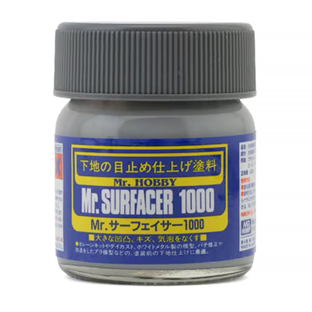 A jar of Mr. Surfacer 1000 contains a grey liquid primer used for scale modeling and surface preparation.