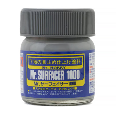 A jar of Mr. Surfacer 1000 contains a grey liquid primer used for scale modeling and surface preparation.