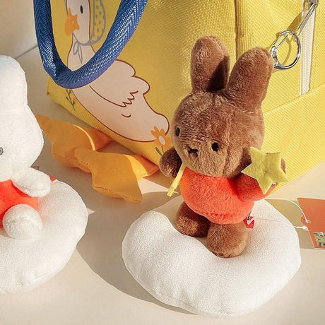 Official Miffy Melanie Dream Mascot Plush Keychains displayed with a yellow tote bag; featuring brown Melanie in orange outfits holding stars, a nostalgic minimalist Zen bag charm set for adult friendship gifts and office-core aesthetics. **perfect Easter basket stuffer for adults**; a minimalist Zen rabbit toy for **Easter Sunday home decor** and nostalgic spring gifting.